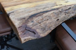 Close-up of a rough, weathered wooden plank with cracks and worn finish.